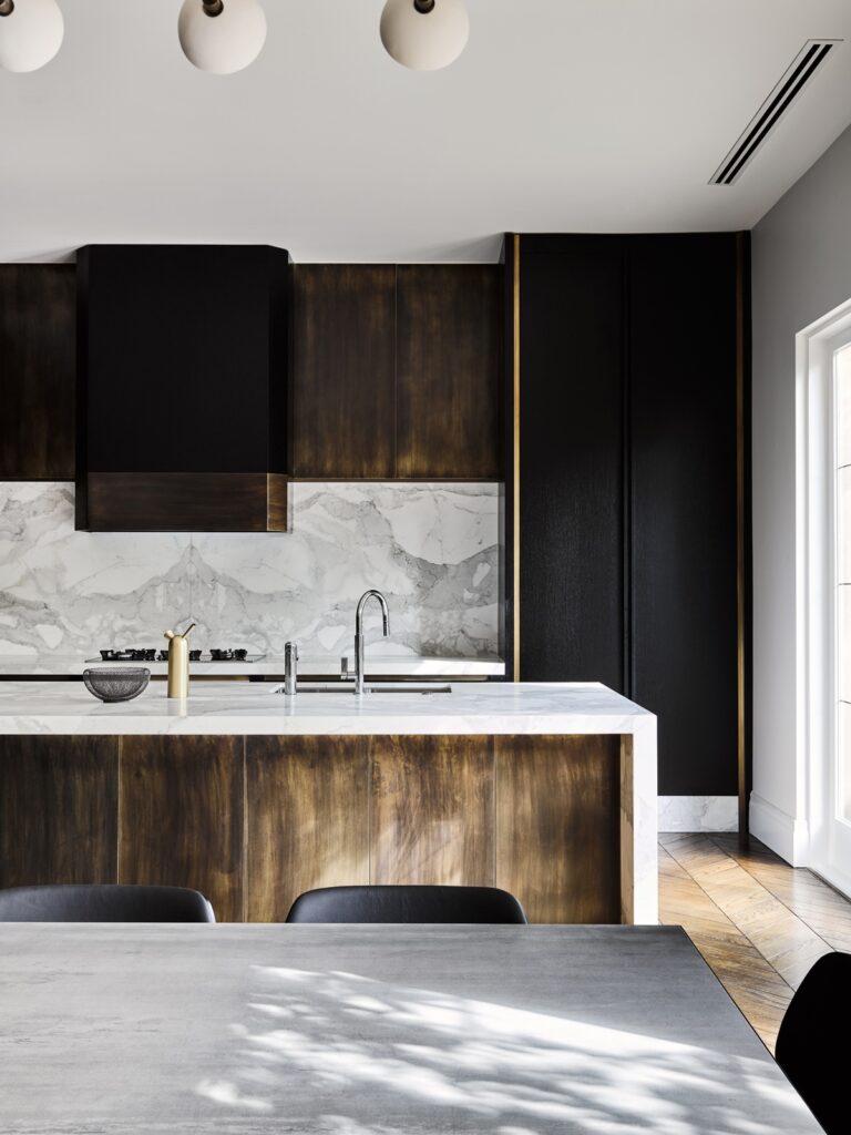 Modern kitchen with wooden floors and black cabinets.