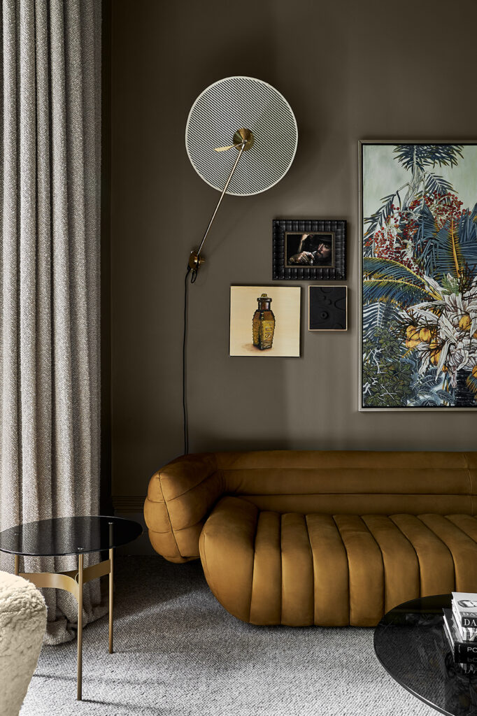 Simone Haag The Whiskey Room living room with green walls and a mustard couch and a lamp and art hanging on the wall