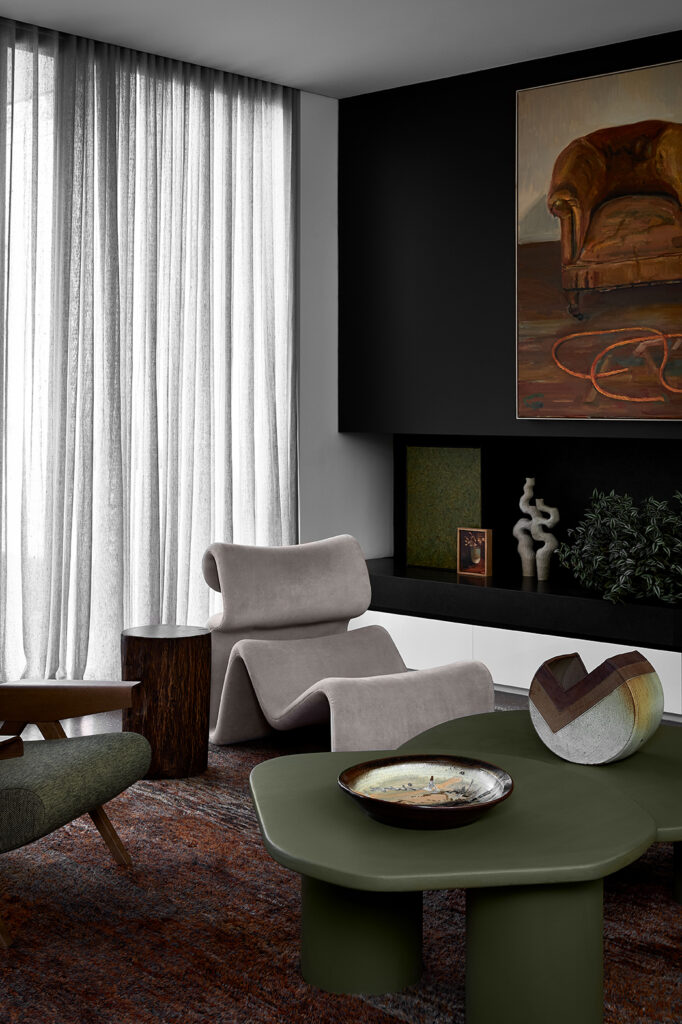 Simone Haag The Whiskey Room living room with a cream velvet armchair and with a green coffee table and with a reddish rug