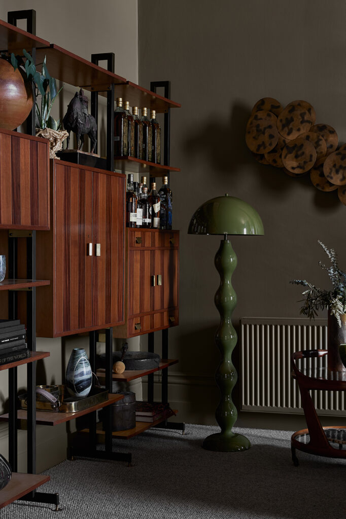 Simone Haag The Whiskey Room corner with green walls and a green standing lamp and with a wood sideboard