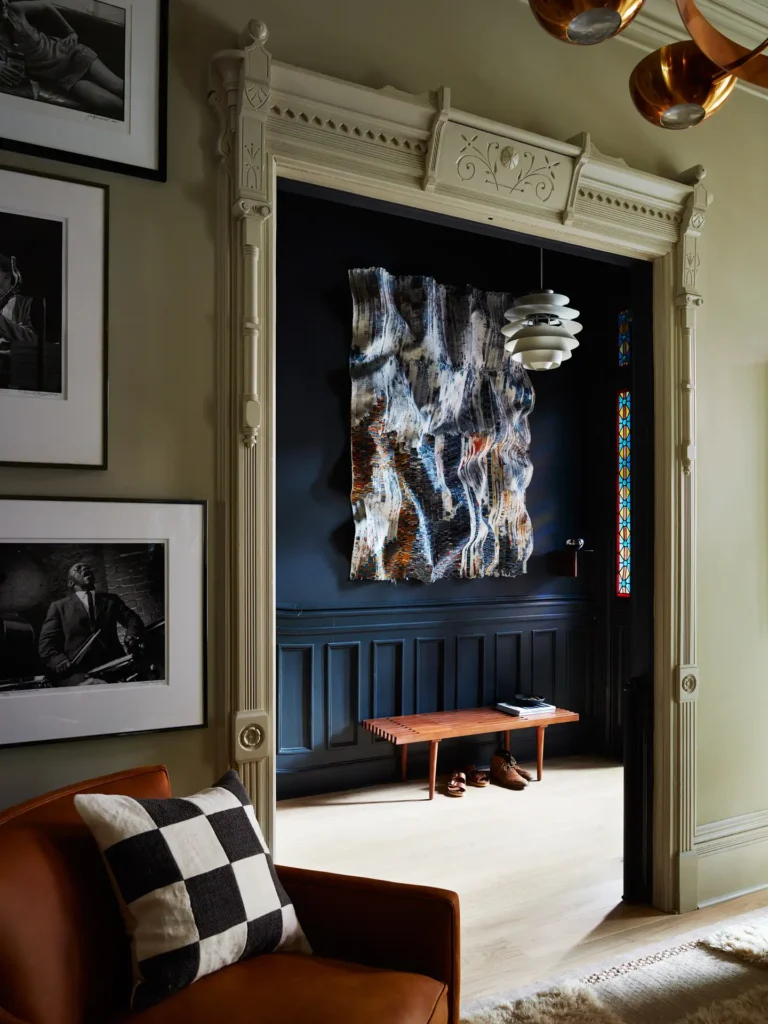 maximalist interior design entryway with blue walls and a bold hanging piece and a wooden bench