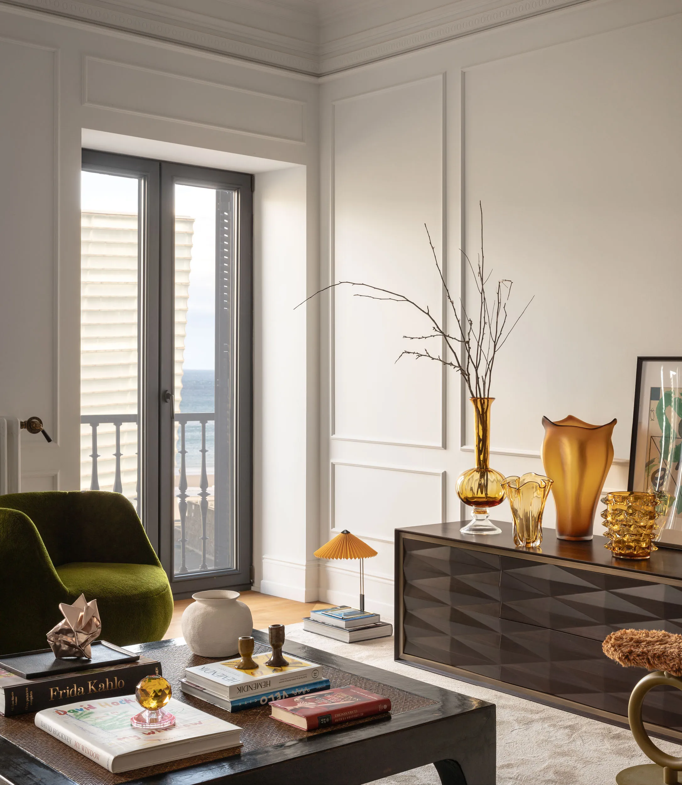 Contemporary Interior Design living room with a velvet green armchairs and with a black wood center table and with decorative molding on the wall and with a wooden sideboard