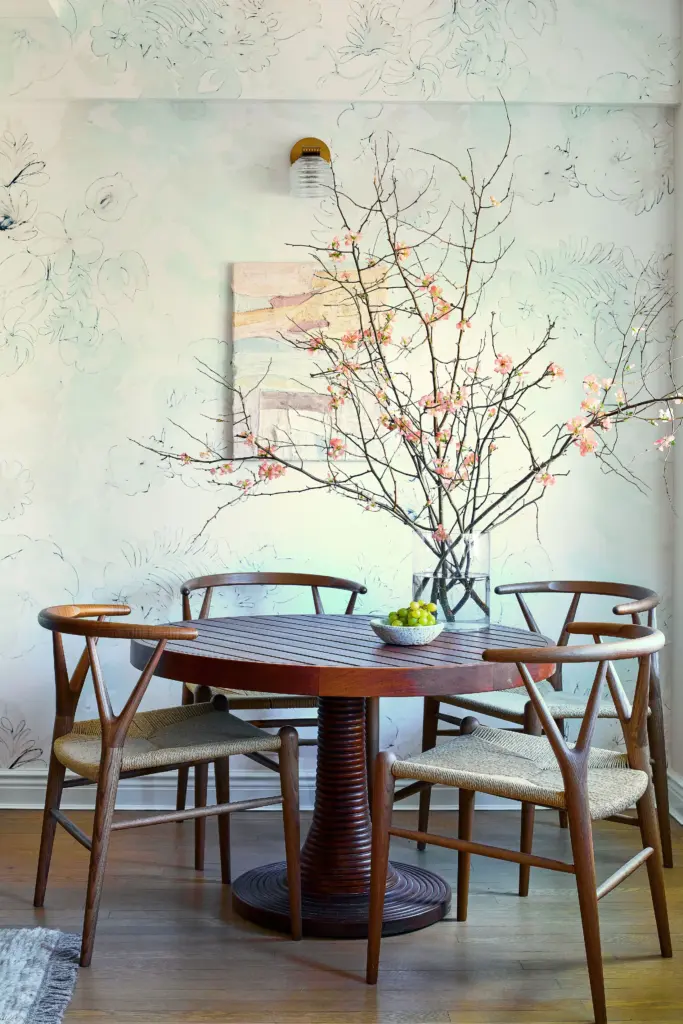 Luxury Apartment dining room with a floral wallpaper and with a round wood dining table and with wood dining chairs and with a flower arrangement on top of the table