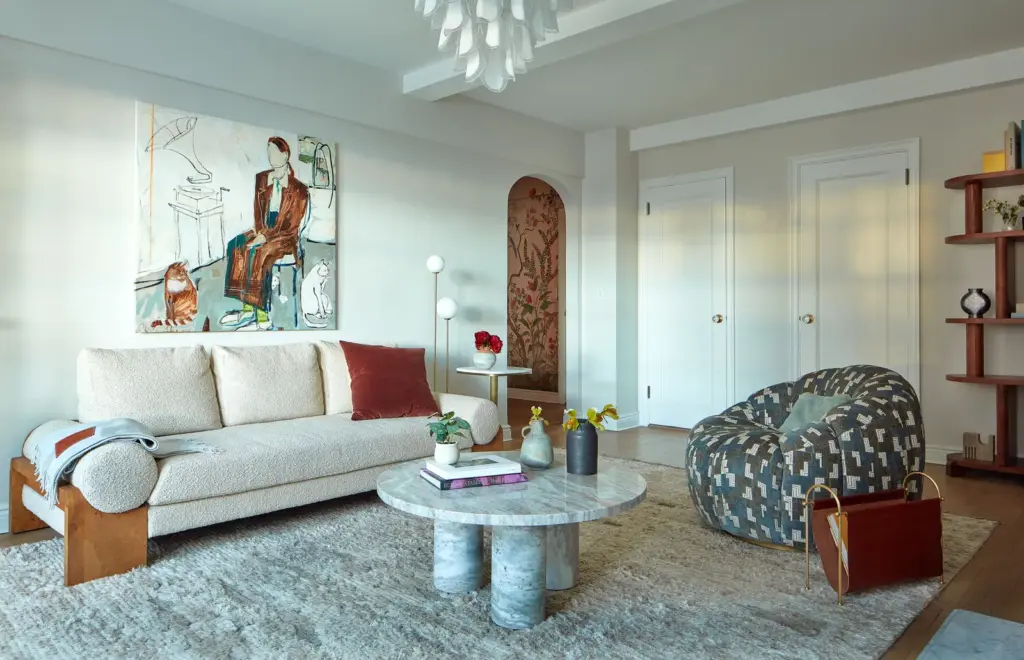 Luxury Apartment living room with white walls and with a bouclé sofa and a travertine center table and with a pattern armchair and with a textured rug