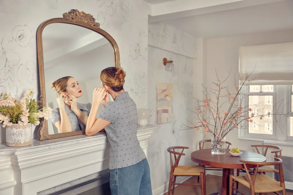 Luxury Apartment living room with a floral wallpaper and with an antique fireplace and with an antique mirror and with a round and wood dining table and with wood dining chairs