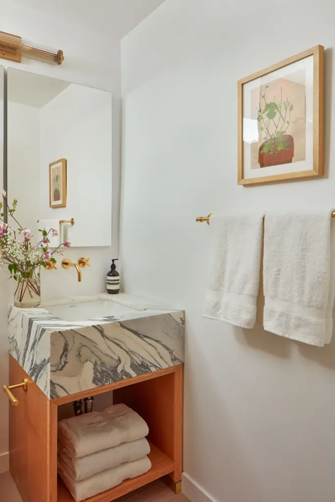 luxury apartment bathroom with a marble sink and with white walls and with pink floors and with a large mirror