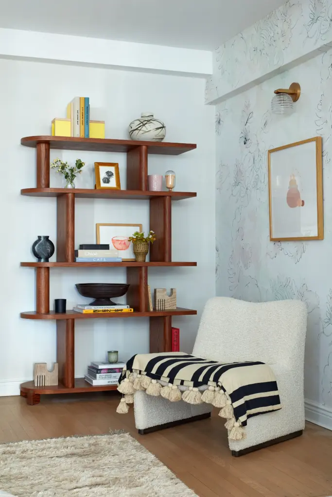 Luxury Apartment living room with a floral wallpaper and with a wood bookcase and with a bouclé armchair