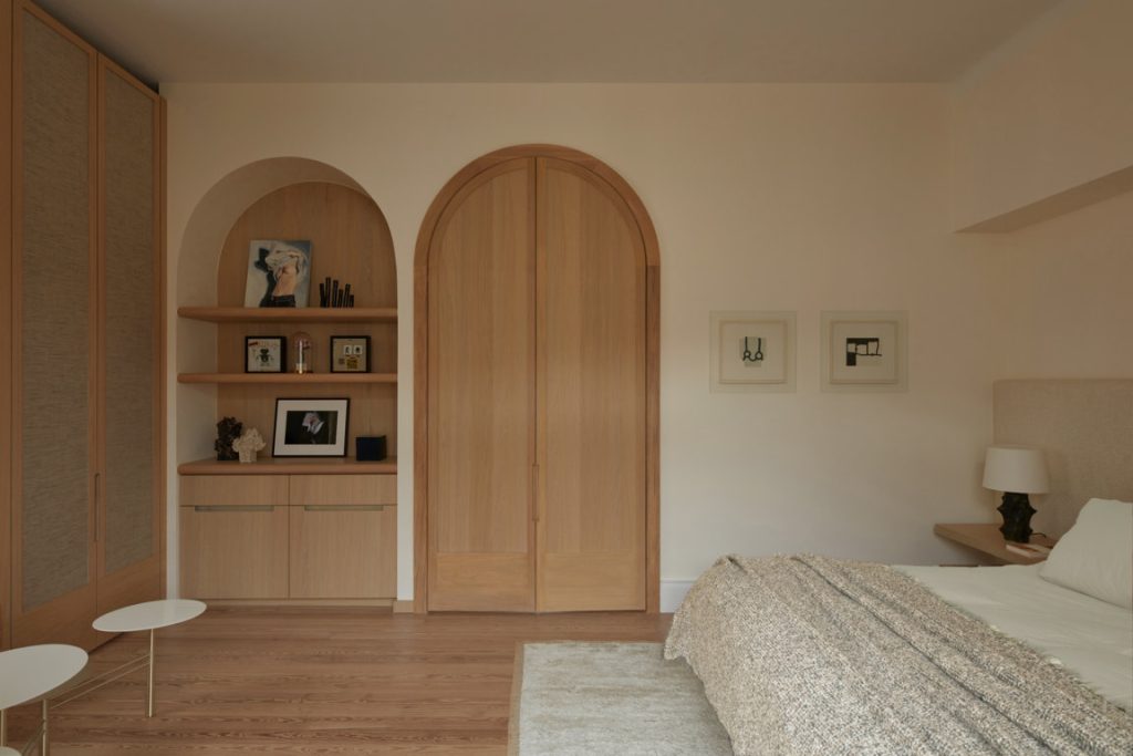 french villa bedroom with cream walls and with built-in shelves and with an arched wood door