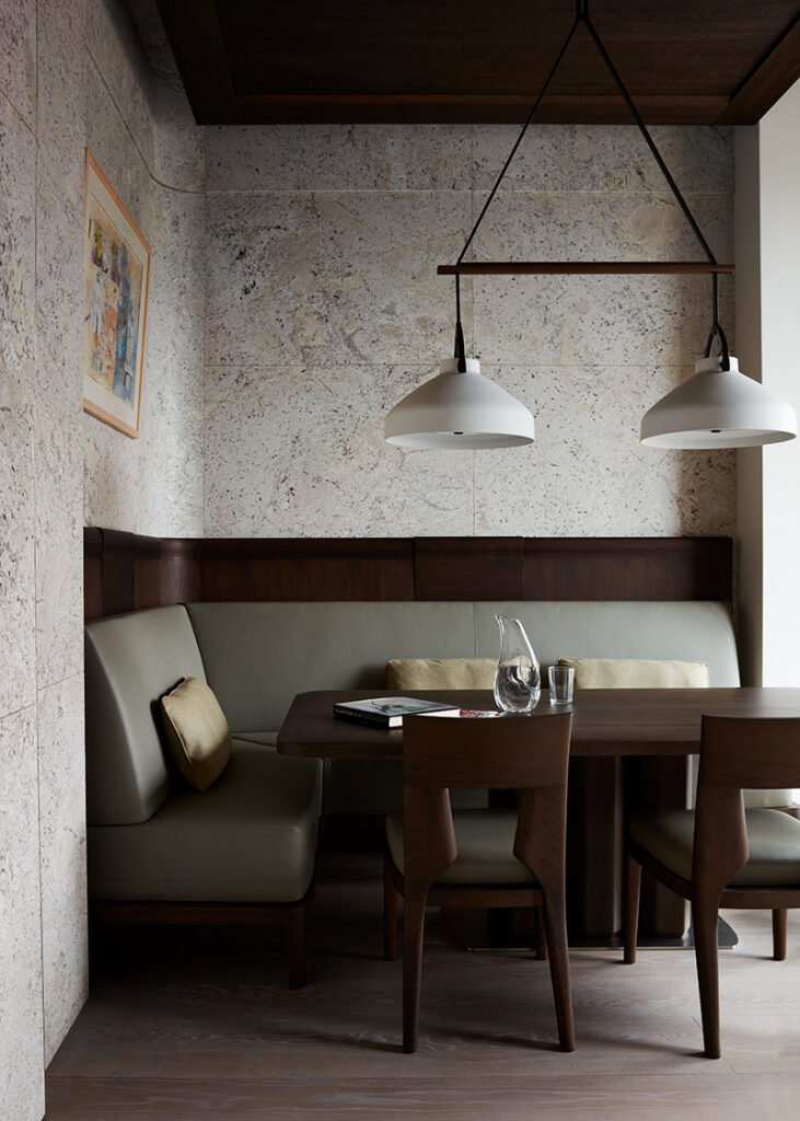 Luxury Interior Design dining room with concrete walls and with a large wood dining table and with wood dining chairs and with a velvet green dining bench