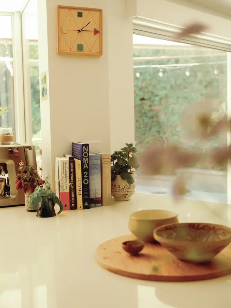 Mid-Century Modern house's kitchen with clean cream walls and with large windows and with a marble countertop and with some personal books