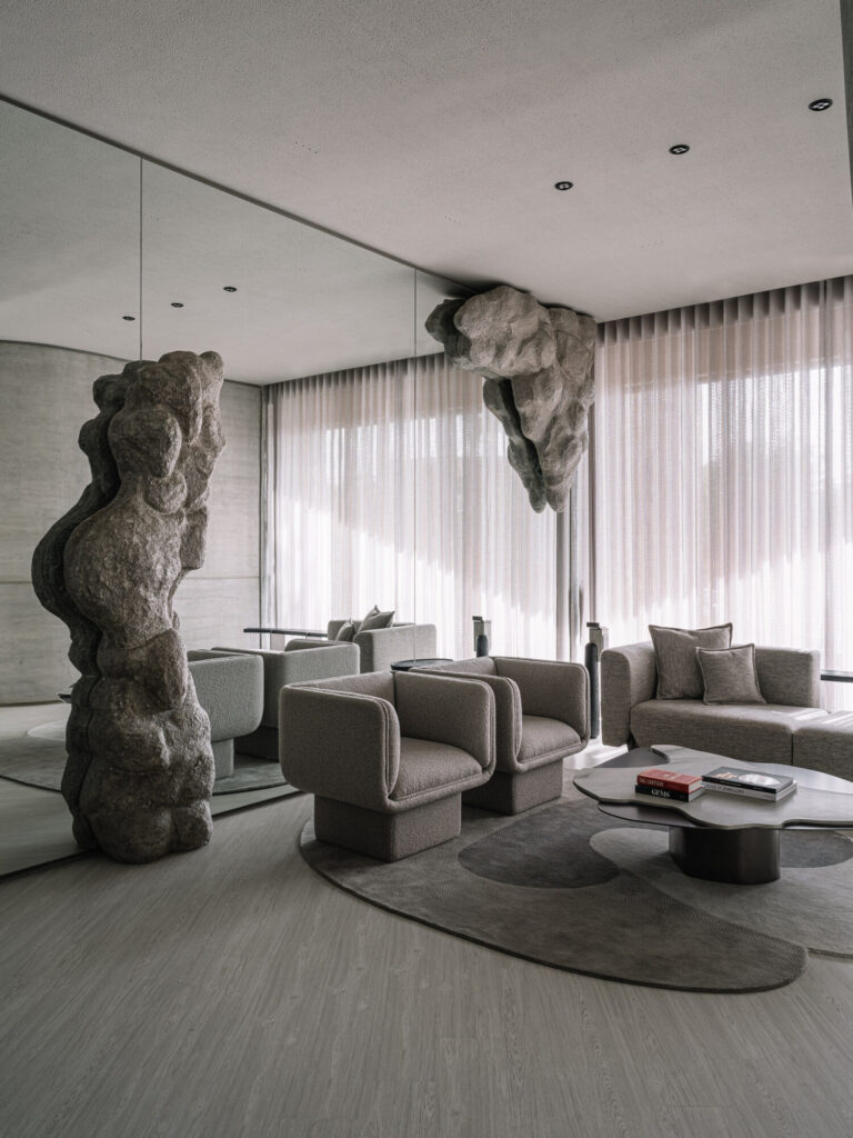 This stunning interior showcases a brutalist design, where raw, sculpted rock formations and minimalist furniture create a dramatic yet refined space.