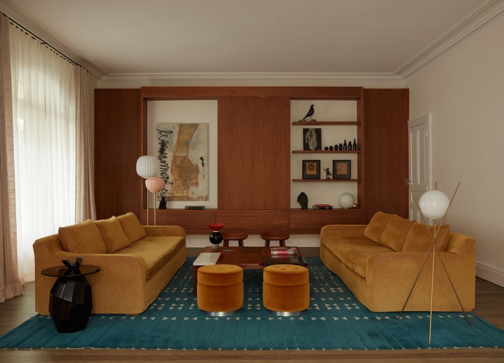 french villa living room with mustard sofas and with a blue rug and with a wooden wall and with a wood center table