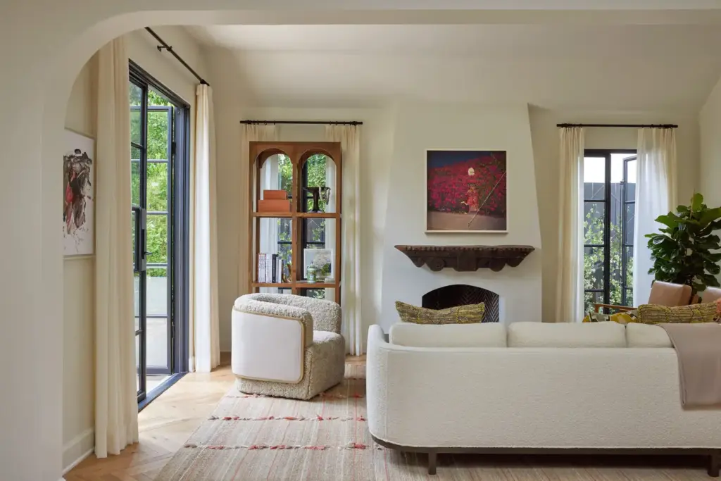 Organic Modernism style living room with cream walls and with large windows and with a cream sofa and with a wool armchair and with a textured cream rug and with a wood cabinet