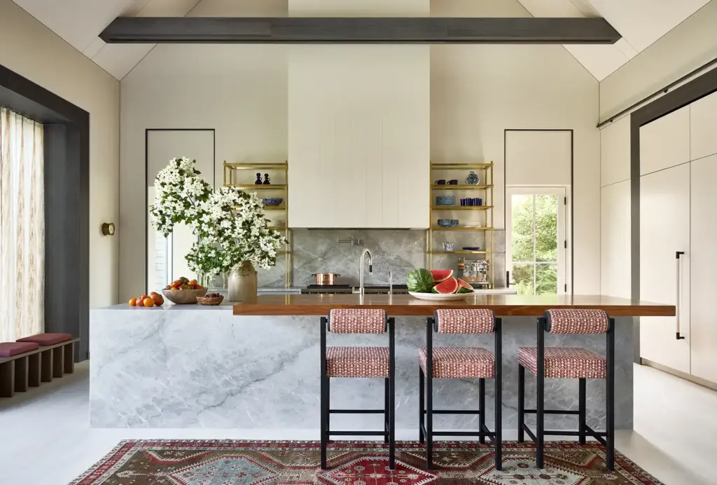 Organic Modernism style kitchen with cream walls and with large windows and with a marble island and with leather stools and with a textured rug