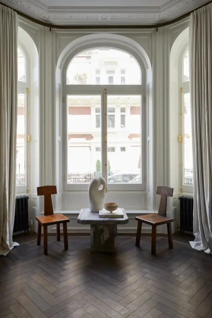 Organic Modernism style living room with arched and large windows and with cream walls and with dark wood floors and with wood chairs and with a stone side table