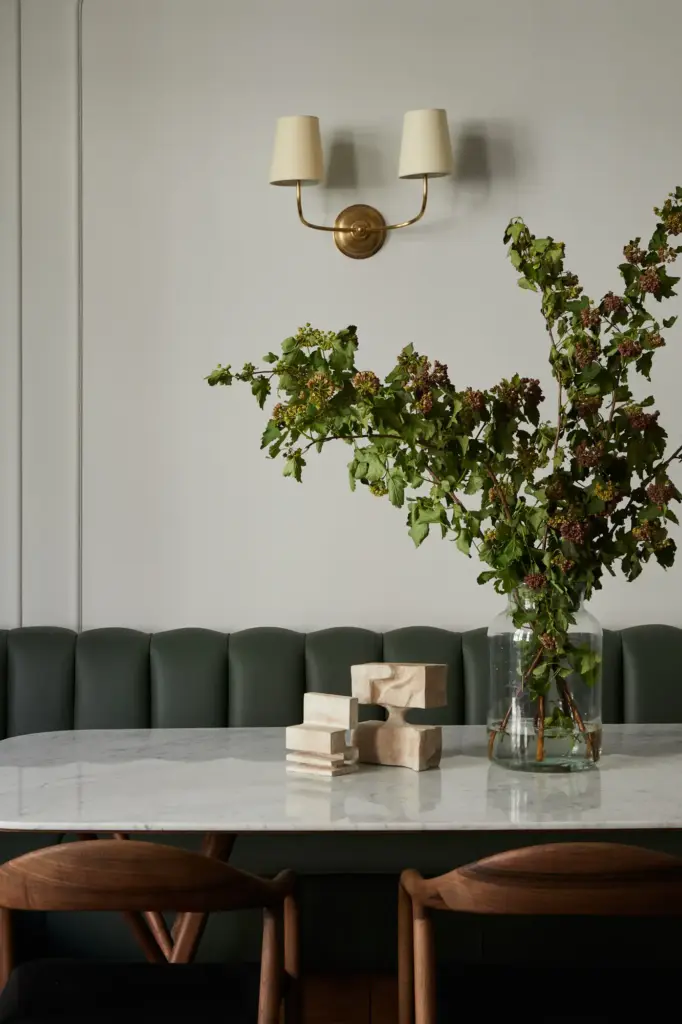 Organic Modernism style dining nook with cream walls and with a leather green bench and with a marble dining table and with wood dining chairs