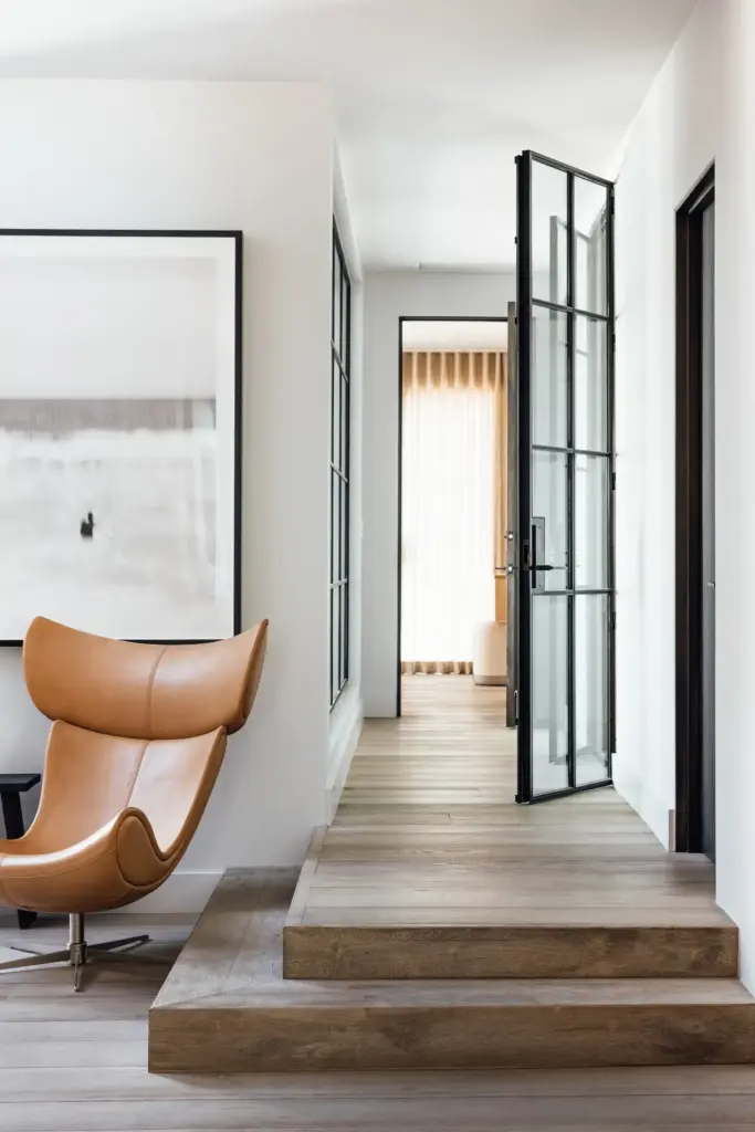 Raw Aesthetics in a living room with wooden floors and with a leather armchair and with a iron door