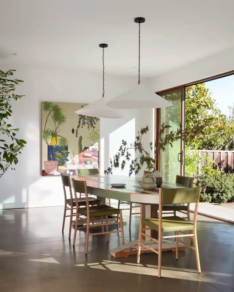 Organic Modernism style dining room with cream walls and with a large window that opens to the outside and with a wood dining table and with wood and leather dining chairs