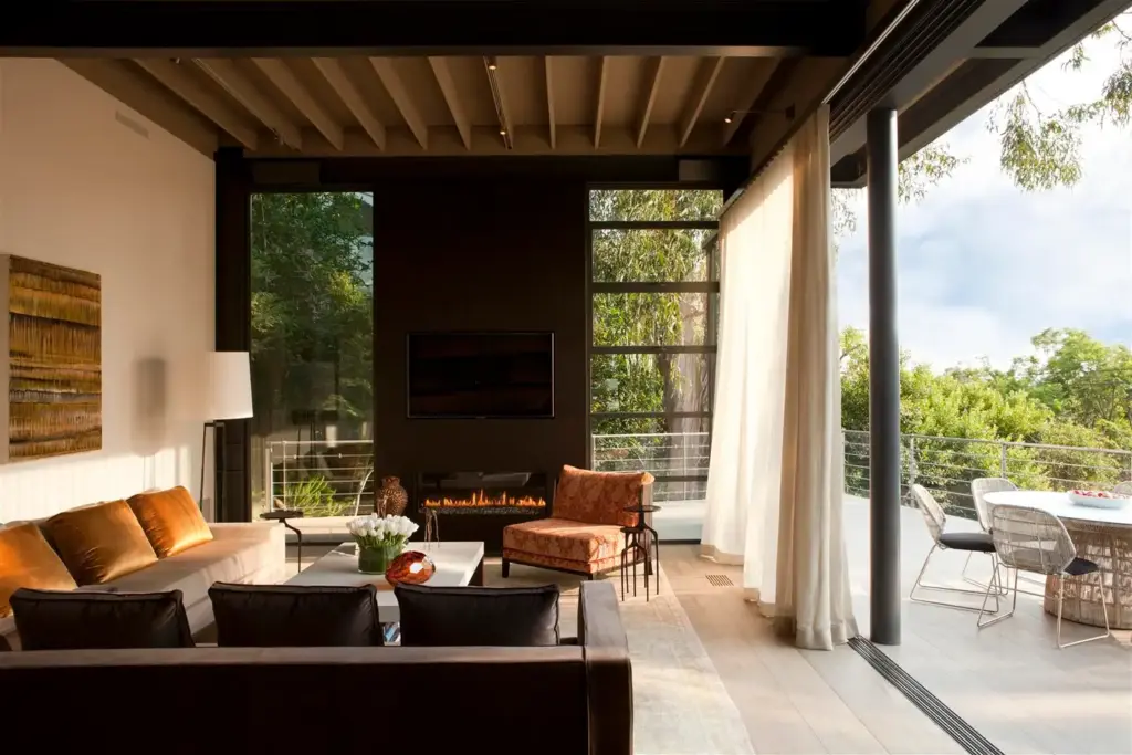 Raw Aesthetics in a living space with a cream wall and with a large window and with a dark brown wall and with a large sectional sofa and a leather armchair