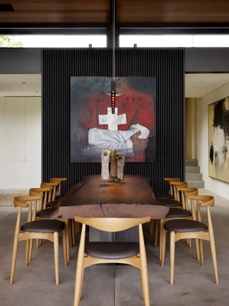 Raw Aesthetics in a dining room with concrete floors and with exposed beams and with a black textured walls and with a wood irregular shape dining table and with wood dining chairs