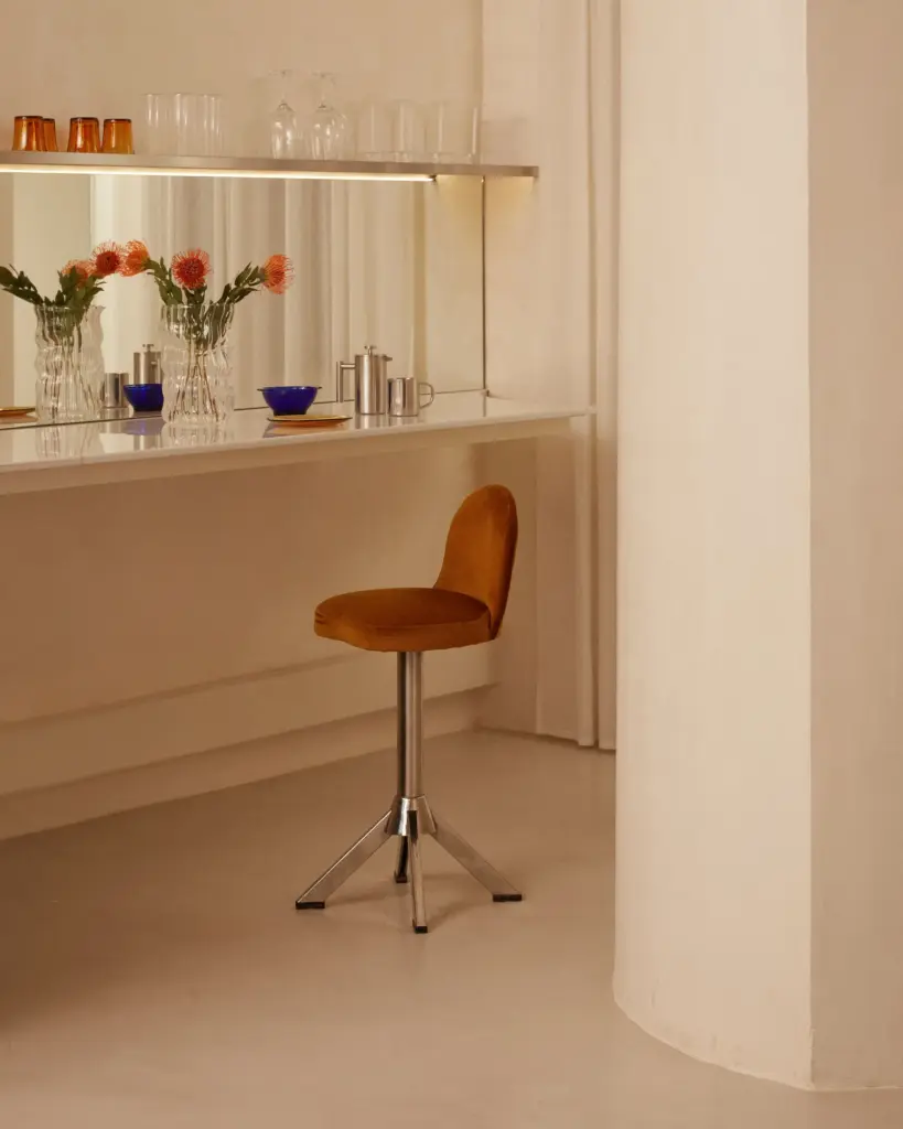 Apartment Renovation kitchen in Barcelona with cream walls and with a large mirror on the walls and with a leather bar stool