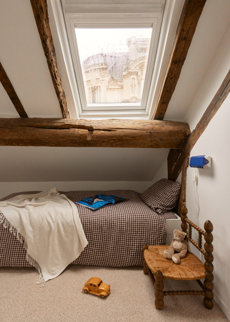 French interior design home kids bedroom with cream walls and large windows and wood exposed beams and small beds