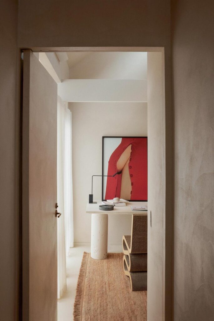 minimalist architecture home office with cream cement walls and with a large window and with a travertine table and with a wooden chair and with a jute rug