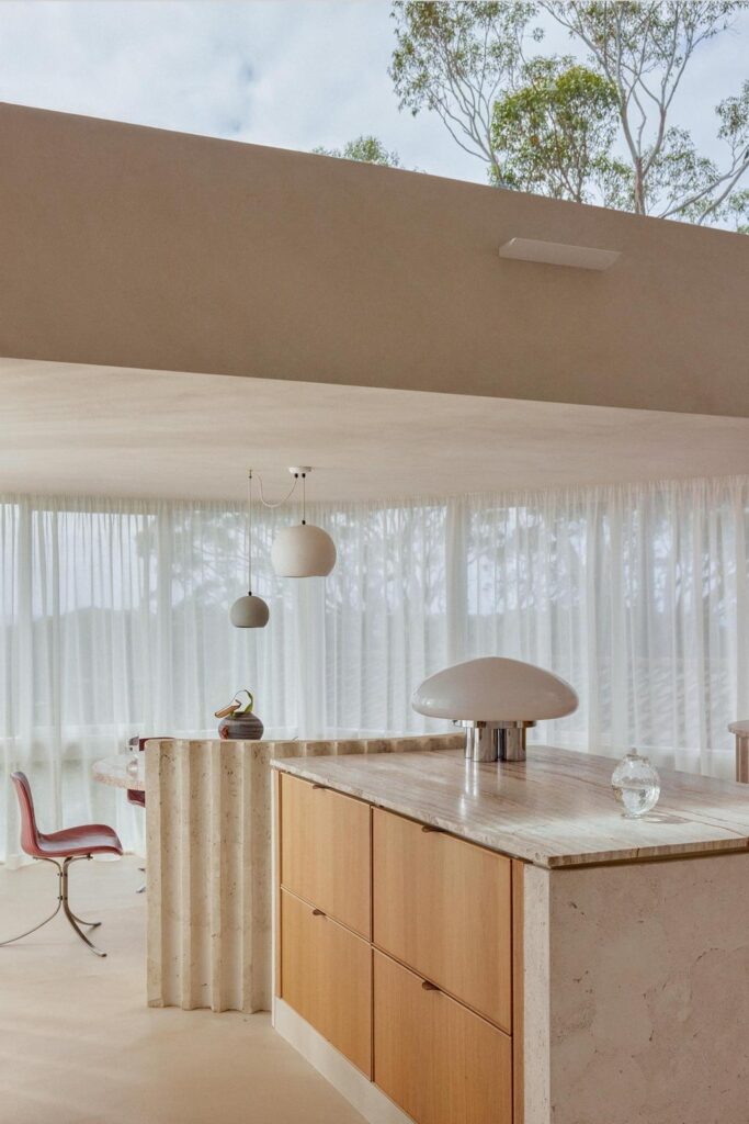 minimalist architecture kitchen with large windows and with a marble island and with wood cabinets and with a travertine table