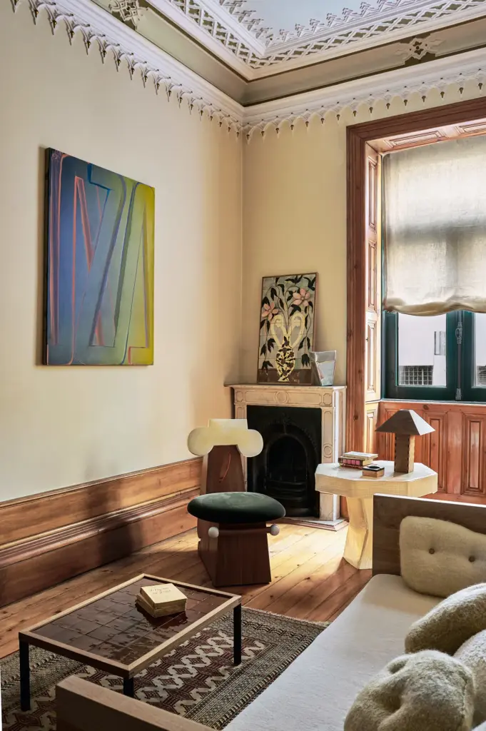 eclectic interior design living room with cream walls and with a large window and with a marble fireplace and with a large sofa and with an accent armchair and with a glass center table and with a textured brown rug