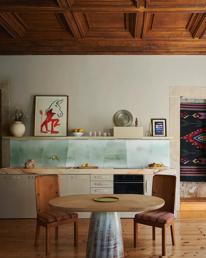 eclectic interior design kitchen with eleaborated wooden ceilings and with white cabinets and with a turquoise blacksplash and with a marble dining table and with two wooden chairs