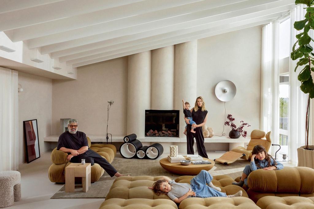 minimalist architecture living room with an inclined ceiling and with exposed beams and with cement walls and with a large velvet green sofa and with a contemporary fireplace and with a large window