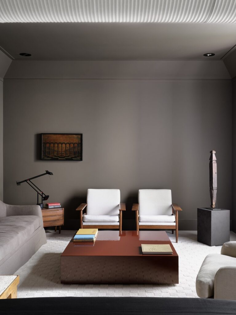 minimalist interior design living room with grey walls and with a grey/brown sofa and with two armchairs and with a wood center table