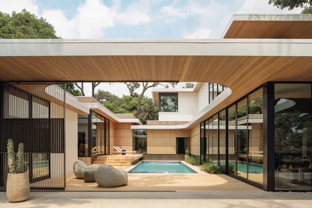 A modern natural home with a courtyard, a swimming pool, and a wooden deck. The home features clean lines and a minimalist design.