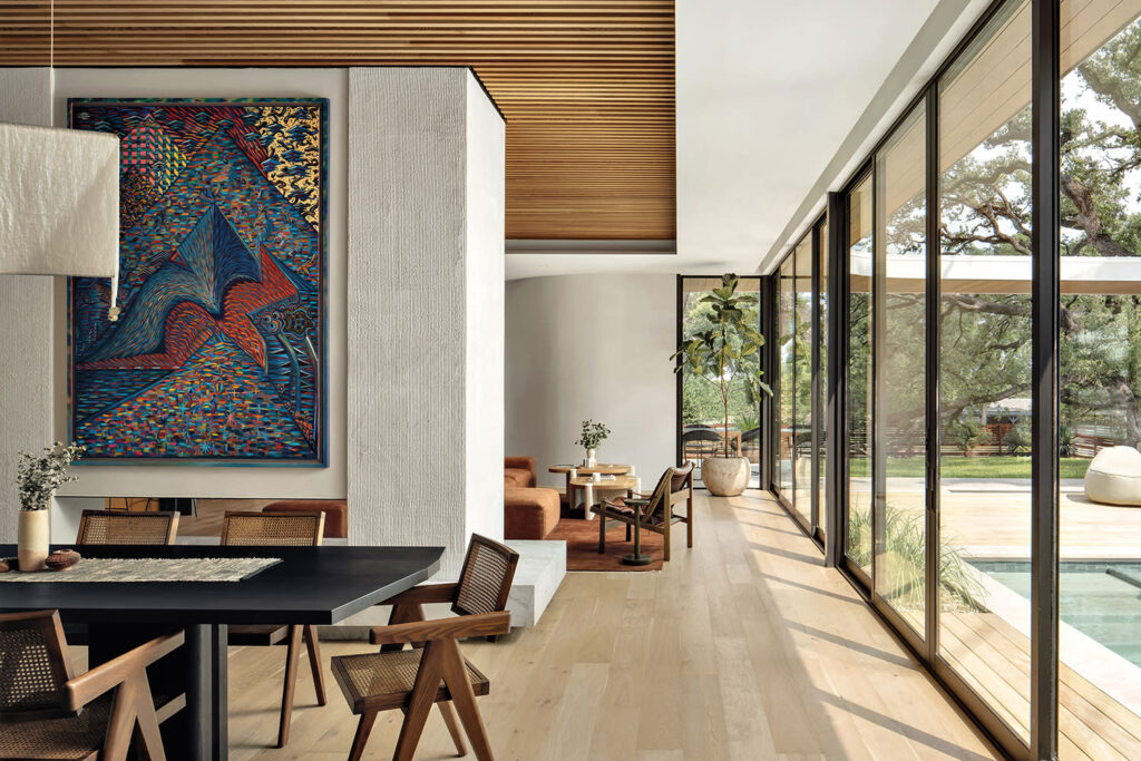 A bright natural home dining area with large windows overlooking a garden. The area features a mix of textures and natural elements.